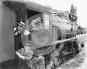 Three men waiting at a steam locomotive