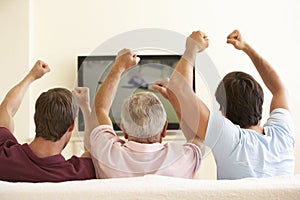Three Men Watching Widescreen TV At Home
