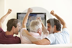 Three Men Watching Widescreen TV At Home