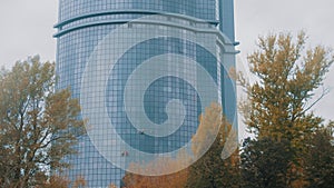 Three men workers hanging on ropes by the exterior windows of a skyscraper - industrial alpinism - autumn time