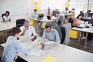 Three men working together in a busy office, elevated view