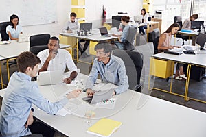 Three men working together in a busy office, elevated view