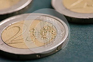 Three metal coins with a face value of two euros are on the table.