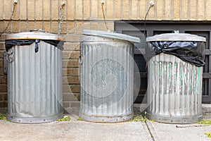 Three Metal Trash Cans Outside in front of a Brick Residential Building in Astoria Queens New York