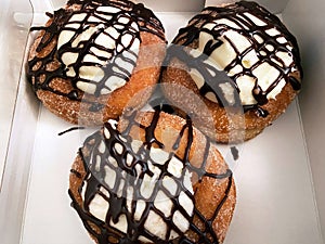Three Mexican Churro Donuts With Cream and Chocolate Toppings photo