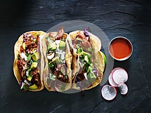 Three mexican pork carnitas tacos flat lay composition