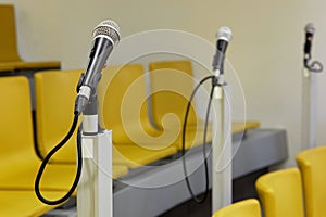 Three microphones in auditorium with yellow photo