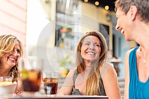 Three middle-aged adult women in a cafe having drinks and having fun