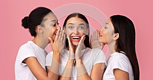 Three Millennial Girls Sharing Secrets Standing Over Pink Background, Panorama