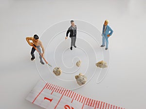 Three mini figure toys arround very small kidney stones top view