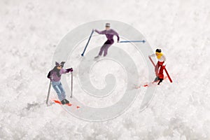 Three mini people skiing in fresh winter snow