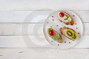 Three mini sandwiches on a plate on wooden background, copy space