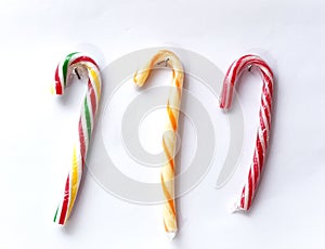 three mint hard candy canes striped in Christmas colours hanging on a white background. Closeup.