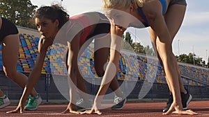 Three mixed-race women standing on a starting line before race, slowmotion