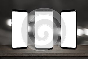 Three mobile phones with screen for mockup on the table photo