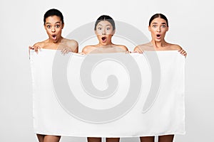 Three Models Posing Holding Bath Towel On White Studio Background