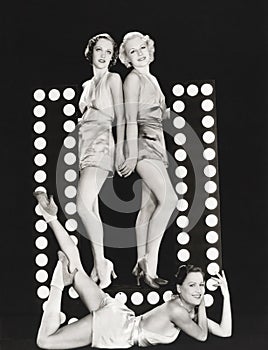 Three models posing by large letter U
