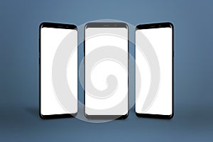 Three modern smartphones with round edges and isolated screen for mockup on blue background photo