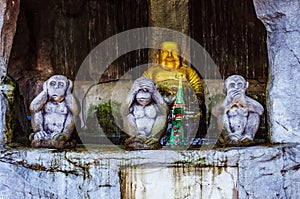 Three monkey statues with Buddha on the background