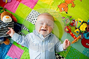 Three months old baby boy, crying at home on a colorful activity