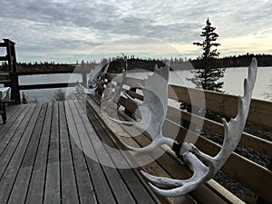 Three moose antlers attached to a wooden bench on a wooden deck of a lake house. Yellowknife, Canada