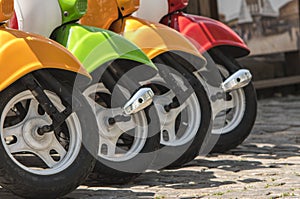 Three mopeds painted in red green yellow colors