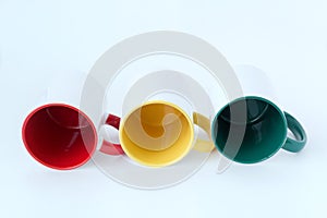 Three mugs red, yellow, green lie on a white background.