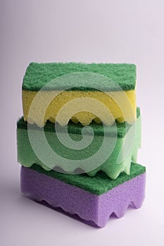 Three multi-colored foam sponges for washing dishes on a white background