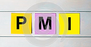 Three multi-colored paper stickers with PMI Project Management Institute text on a blue wooden background