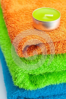 Three multi colored terry towels and candle