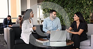 Three multi-ethnic teammates talking met in office lobby