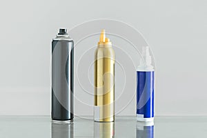 Three multicolored bottles of professional hair spray on white background