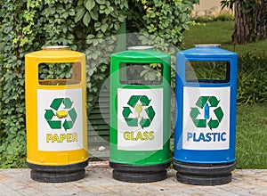 Three multicolored recycle bins for waste with icons for the convenience of sorting junk waste in the garden photo