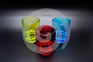 Three multicolored shot glasses on black background