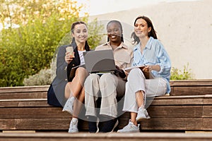 Three multicultural girlfriends students resting at university campus