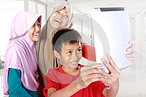 Three muslim kids playing tablet computer