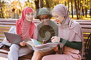 Three Muslim Students Women Learning Together Using Computer Sitting Outdoors
