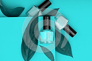 Three nail polish bottles on green background. Nail polish bottles decorated with blue leafs