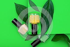 Three nail polish bottles on green background. Nail polish bottles decorated with green leafs