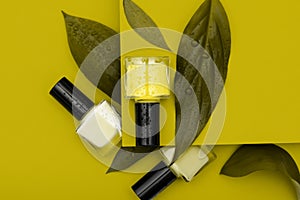 Three nail polish bottles on yellow background. Nail polish bottles decorated with green leafs