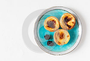 Three national traditional cakes from Portugal - pastry Pastel de nata of custard yolk cream on a plate of Azulejo with