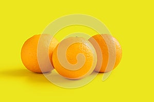 Three navel oranges on yellow background