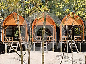 three neatly arranged beach huts surrounded by mangrove forest trees