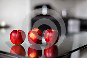 Three nectarines on the glass table