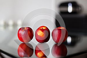 Three nectarines on the glass table