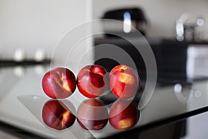 Three nectarines on the glass table