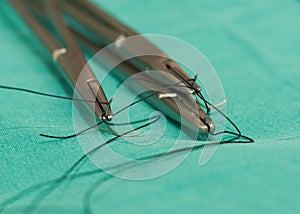 Three needle holders and needles with sutures