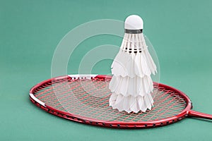 Three new badminton shuttlecock with rackets on green mat court