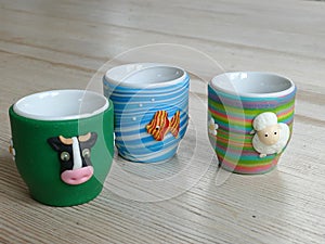 Three novelty eggcups on a wooden table
