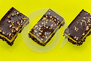 Three nutty brownie bars on a yellow background